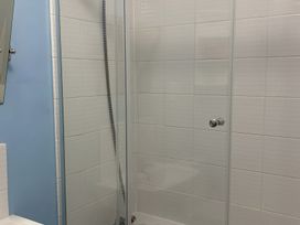 A shower with tiles and a mirror at Edal Court in Sheringham