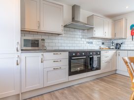 A kitchen with cabinets, oven, microwave and kettle at Groeslon Uchaf in Caernarfon