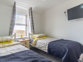 A bedroom with two beds and a television at Groeslon Uchaf in Caernarfon