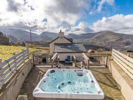 An outdoor area with a hot tub and mountain views at Groeslon Uchaf in Caernarfon