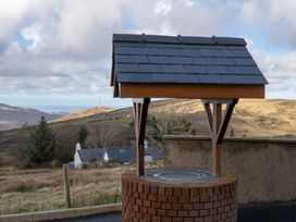 A well with a roof in a rural landscape at Groeslon Uchaf in Caernarfon