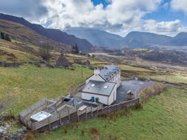 An outdoor view of a house with a hot tub and mountain backdrop at Groeslon Uchaf in Caernarfon