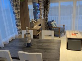 A living room with a dining table and an armchair at Lighthouse Lodge in Mablethorpe