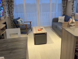 A living room with a sofa and armchair at Lighthouse Lodge in Mablethorpe