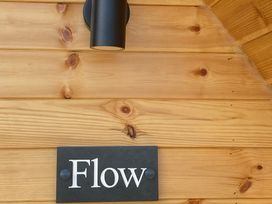 A wooden wall with a light fixture and a sign labeled Flow at Kirkapol Beach Pod - Flow Isle of Tiree