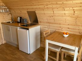 A kitchen area with sink, kettle, toaster, induction hob and a table with oranges at Kirkapol Beach Pod - Flow Isle of Tiree