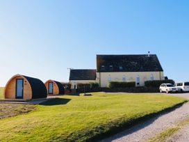An outdoor view of two pods and a house at Kirkapol Beach Pod - Flow Isle of Tiree