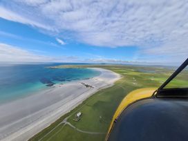 An aerial view of a beach and green land at Kirkapol Beach Pod - Flow Isle of Tiree