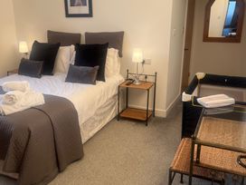 A bedroom with a bed, side table, lamp, and a cot at 4 Bickington Road Barnstaple