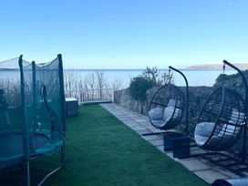 An outdoor garden area with a trampoline and hanging chairs at Blue Haven Penmaenmawr