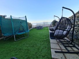 A garden with a trampoline and hanging chairs at Blue Haven in Penmaenmawr