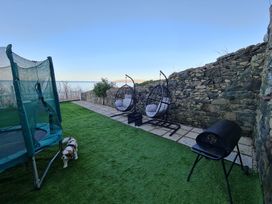 An outdoor area with a trampoline and hanging chairs at Blue Haven in Penmaenmawr