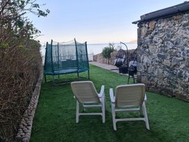 A garden with sun loungers and a trampoline at Blue Haven in Penmaenmawr