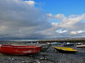 Boats on a rocky shore near a seawall with clouds in the sky at Blue Haven in Penmaenmawr