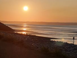 A sunset over the sea with a person walking on the beach at Blue Haven in Penmaenmawr