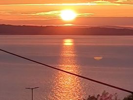 A sunset over water with clouds at Blue Haven in Penmaenmawr