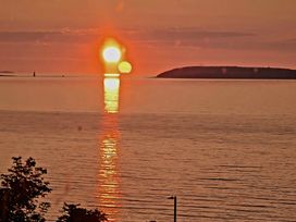 A sunset over the ocean with reflection in the water at Blue Haven in Penmaenmawr