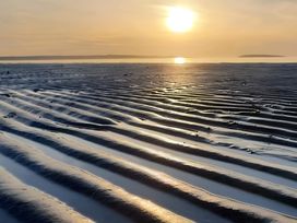 A beach with rippled sand and sunlight at Blue Haven Penmaenmawr
