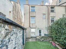 A garden with a building and stone wall at Blue Haven in Penmaenmawr