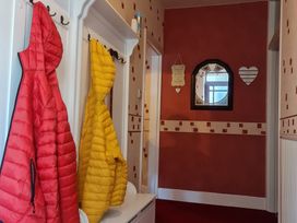 A hallway with red and yellow coats hanging on hooks at Sea View Escape in Penmaenmawr