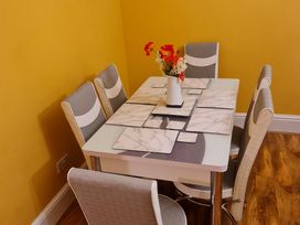 A dining table with six chairs and a vase with flowers at Sea View Escape in Penmaenmawr