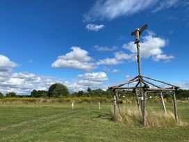 A wooden structure in a grassy field at Cotswold Nights Away 1 Evesham