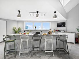 A kitchen with a counter, bar stools, and appliances at Huxham View and Annex Stoke Canon