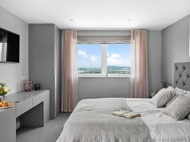 A bedroom with a bed, television, and window at Huxham View and Annex Stoke Canon