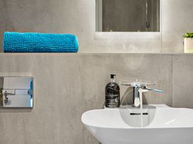 A bathroom with a sink, towel, soap dispenser, and mirror at Huxham View and Annex Stoke Canon