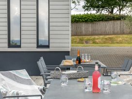 A patio with a table, chairs, and drinks at Huxham View and Annex in Stoke Canon