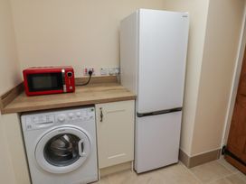 A utility room with a washing machine, microwave, and refrigerator at Sunny Brae in Alnwick