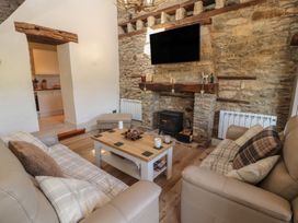 A living room with a sofa, coffee table, and fireplace at Tullythwaite Barn Kendal