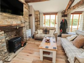 A living room with a fireplace, sofas, and a coffee table at Tullythwaite Barn in Kendal