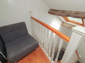A staircase with a sofa and wooden handrail at Tullythwaite Barn in Kendal