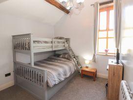 A bedroom with a bunk bed and a side table at Tullythwaite Barn in Kendal