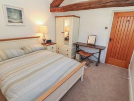 A bedroom with a bed, wardrobe, desk, and lamp at Tullythwaite Barn in Kendal