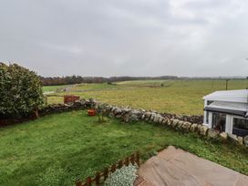 A garden with a stone wall and grass at 1 Sunnybrae in Alnwick