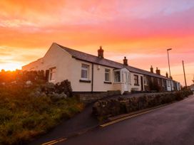 A house with a stone wall and road at 1 Sunny Brae in Embleton