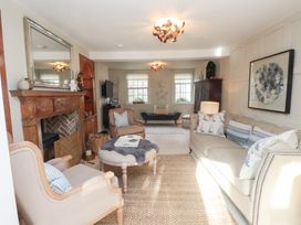 A living room with a sofa, armchair, and coffee table at The Music Box in Beaumaris