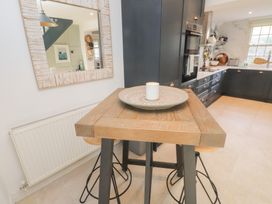 A kitchen with a wooden table and stools at The Music Box in Beaumaris