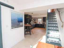 A kitchen with a staircase and dining area at The Music Box in Beaumaris