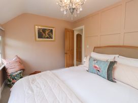 A bedroom with a bed, painting, and chair at The Music Box in Beaumaris