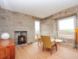 A living room with a fireplace and chairs at Boscabrea near Tintagel