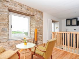 A living room featuring a table and chair with a plant at Boscabrea near Tintagel