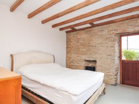A bedroom with a bed, nightstand, and window at Boscabrea near Tintagel