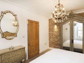 A bedroom with a chandelier and wardrobe at Tri Raglan Bach in Beaumaris