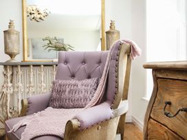 A chair with a cushion and blanket in a living room at Tri Raglan Bach Beaumaris