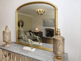A living room with a mirror and decorative objects at Tri Raglan Bach in Beaumaris