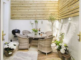 An outdoor patio with a table and chairs at Tri Raglan Bach in Beaumaris