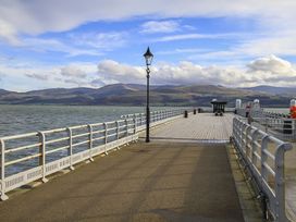 A pier extending over water with mountains and clouds at Tri Raglan Bach Beaumaris